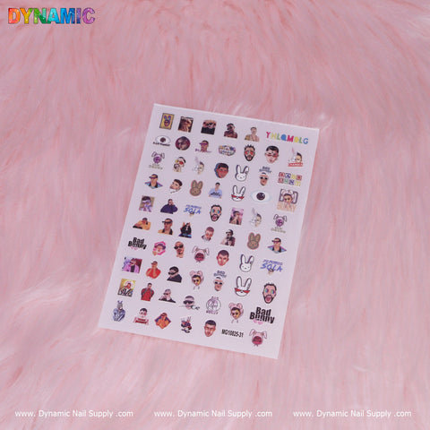 The sticker sheet on a pink fur background displays an array of small illustrations, such as cartoon faces, characters, and logos. "DYNAMIC" is prominently featured at the top in vibrant designs similar to Hip Hop Stickers. The bottom edge shows Dynamic Nail Supply branding and website details. This is the Bad Bunny, Hip Hop Sticker (MG10825-31) by Dynamic Nail Supply.