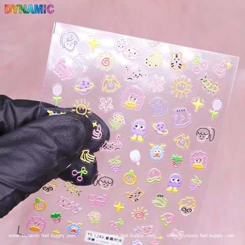 A gloved hand showcases a sheet of Colorful Kid Hand Drawing Stickers (TS-1249) against a pink backdrop, capturing the playful essence of children's art with designs like animals, smiley faces, and flowers. In the top left corner is the DYNAMIC logo, and beneath it reads Dynamic Nail Supply.