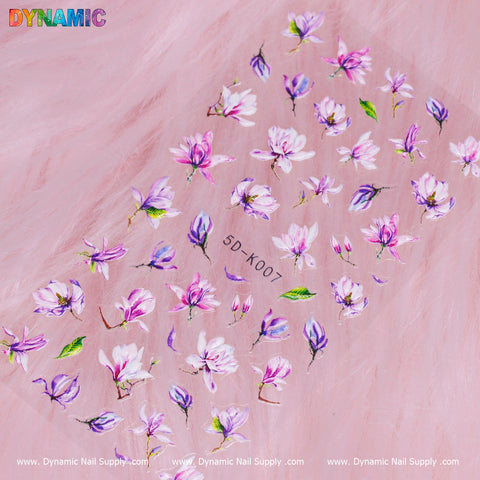 The Floral Sticker (5D-K007) from Dynamic Nail Supply showcases a pink backdrop adorned with purple and pink flowers, complemented by green leaves in various sizes. The design includes a vibrant DYNAMIC logo in the upper left corner, while www.DynamicNailSupply.com is repeated three times at the bottom.