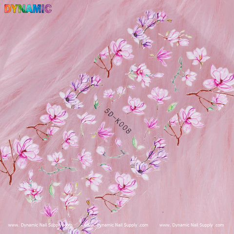 A sheet of Floral Sticker (5D-K008) is beautifully showcased against a soft pink fur backdrop, featuring charming pink and purple floral designs with delicate flowers and branches. The word "Dynamic" is prominently displayed at the top, while text at the bottom introduces Dynamic Nail Supply as the brand behind this exquisite sticker collection.