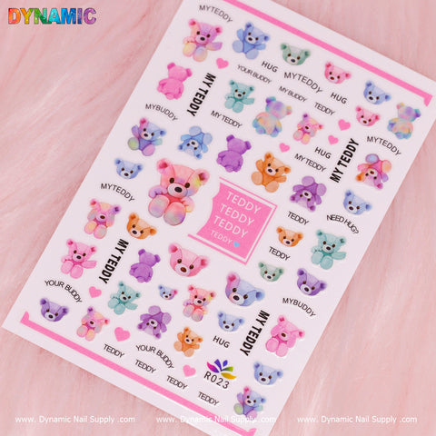 The Teddy Bear Sticker (R023) from Dynamic Nail Supply showcases vibrant Teddy Bear designs in pastel shades such as pink, blue, and purple. Each sticker is labeled with text like TEDDY, MY TEDDY, MY BUDDY, and HUG on a pink background featuring the Dynamic Nail Supply watermark throughout.