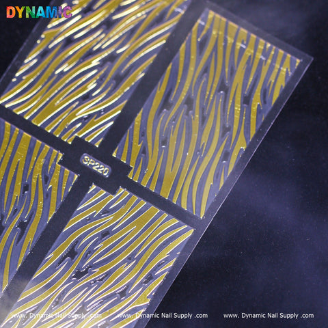A close-up of the Animal Pattern Nail Sticker (SP220), a transparent sheet embellished with golden flame-shaped nail decals, exudes a dynamic, flowing appearance. The Dynamic Nail Supply branding is elegantly positioned in the top left corner. Placed on a dark surface, this design provides an intriguing touch reminiscent of an animal pattern.