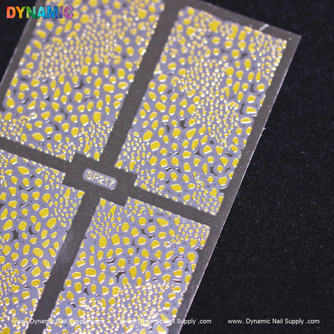 Close-up of an Animal Pattern Nail Sticker sheet from Dynamic Nail Supply, displayed on a black surface. The sticker features leopard print with striking yellow and silver spots. The partially visible sheet highlights the word "DYNAMIC" in colorful letters at the top left, alongside the product code SP217, bringing a touch of fierce elegance to your nail art collection.