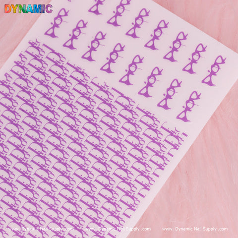 A sheet from the Luxury Water Decal (Neon Purple) collection by Dynamic Nail Supply features stylized glasses and bows in neon purple set against a soft pink background. The DYNAMIC logo is prominently displayed in colorful letters at the top left corner, with www.DynamicNailSupply.com appearing in white text along the bottom edge.