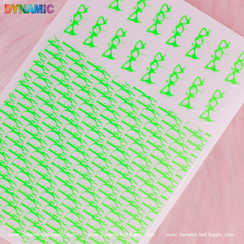 A sheet of Luxury Water Decal (Neon Green) by Dynamic Nail Supply delicately rests on a pink surface, showcasing adorable cat-shaped nail stickers with bows, glasses, and simple silhouettes. Arranged in rows, these luxurious water decals exude elegance under the Dynamic Nail Supply brand name at the top and bottom edges.