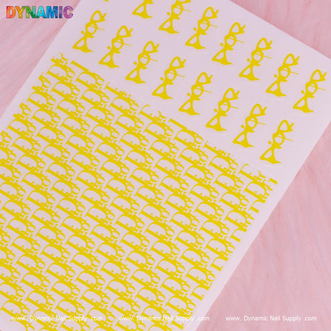 A sheet of the Luxury Water Decal (Yellow) from Dynamic Nail Supply showcases exquisite yellow nail art stickers against a pink backdrop, adorned with bows and various sizes of cat silhouettes. The top and bottom margins elegantly display the text “Dynamic Nail Supply” repeatedly.