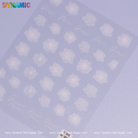 A sheet of Transparent Flower Sticker features white floral designs and the word "flower" on a translucent background. The vibrant logo of Dynamic Nail Supply is prominently displayed at the top left, with their website, www.DynamicNailSupply.com, repeated along the bottom edge.