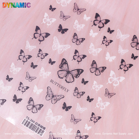 A collection of Black and White Butterfly Stickers (TS-390) is displayed on a soft pink surface. The largest butterfly, labeled BUTTERFLY, takes center stage. The brand name Dynamic Nail Supply appears in colorful letters at the top left, while small text and a barcode are visible at the bottom.