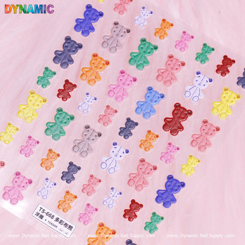The Colorful Teddy Bear Sticker (TS-668) from Dynamic Nail Supply showcases a vibrant assortment of bears set against a pink fuzzy backdrop. With different sizes and hues such as red, blue, and green, these lively designs feature the "DYNAMIC" branding along the edges.