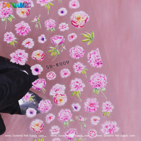 The Floral Sticker (5D-K009) from Dynamic Nail Supply features a variety of pink peony designs with green leaves, depicting everything from full blooms to small buds. It has a soft pink background with "DYNAMIC" elegantly printed at the top, highlighting the beauty of 5D artistry.