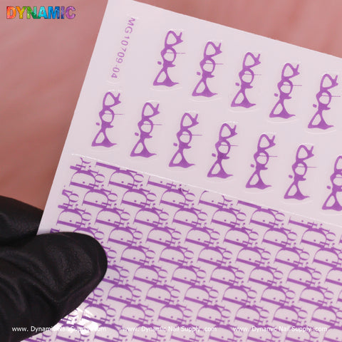 A sheet from Dynamic Nail Supply’s Luxury Water Decal collection showcases cat faces with glasses set against a vibrant neon purple background, arranged neatly in rows. The brand name, DYNAMIC, appears in colorful letters at the top left, displayed by a gloved hand against a pink backdrop.