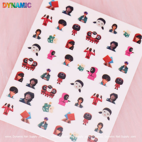 Sticker sheet from Dynamic Nail Supply called "Squid game 01 (sq game)," showcasing small cartoon characters in unique outfits and masks reminiscent of Squid Game. Some characters hold shapes like circles and squares. The background is white, featuring the DYNAMIC logo at the top-left corner, with "Dynamic Nail Supply" repeated at the bottom.