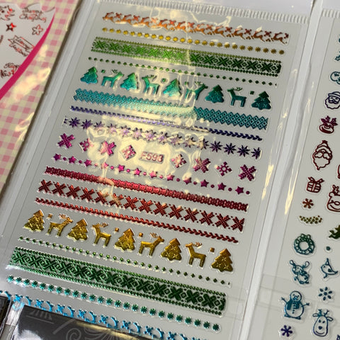 This Bundle of 20pcs Christmas Nail Stickers from Dynamic Nail Supply, priced at $30, showcases holographic designs featuring reindeer, trees, snowflakes, stars, and geometric patterns. Available in shades of green, red, purple, and gold, these festive stickers are arranged in parallel horizontal rows for a decorative nail art experience.