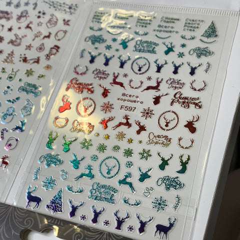 The Bundle of 20pcs Christmas Nail Stickers from Dynamic Nail Supply, priced at $30, features a festive theme with colorful holographic designs of reindeer heads, Christmas trees, snowflakes, and holiday greetings in Cyrillic script. These vibrant stickers are available in red, green, turquoise, and purple on a transparent background.