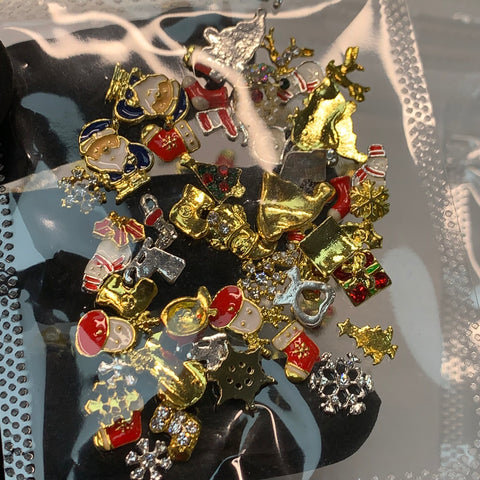 The "50 pcs Christmas Charms for Winter Nails Art Design" by Dynamic Nail Supply is a clear plastic bag filled with a festive assortment of colorful nail art charms, featuring miniature Santa faces, snowflakes, reindeer, Christmas trees, and bells in red, gold, and white accents—ideal for creating Christmas-themed designs.