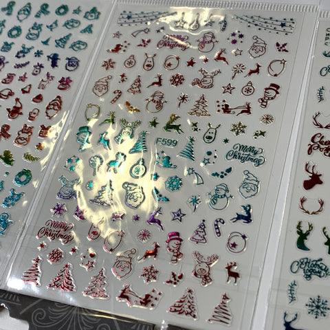 Close-up of the Dynamic Nail Supply Bundle of 20pcs Christmas Nail Stickers, priced at $30, showcasing festive designs. These transparent sheets are adorned with Santa Claus, snowflakes, Christmas trees, reindeer, and phrases like "Merry Christmas," highlighted with metallic red and teal accents. Perfect for adding holiday cheer to your nails!