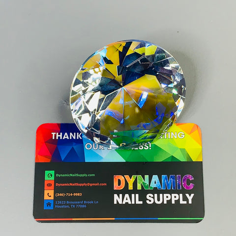 A 6cm (2.3") Display Diamond made from K9 Crystal, designed for decoration, is placed on top of a vibrant business card from Dynamic Nail Supply. The card showcases the phone number and email address against a rainbow-colored background and features the message, "Thank you for supporting our business!