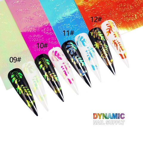 A display features long stiletto-shaped nails adorned with colorful tropical leaf designs, highlighted by holographic leaves from the Hot Design 16pcs/set - Holographic Leaves Sticker for Nail Art Decoration. The nails are arranged in sets numbered 09# to 12#, and vibrant foil strips in green, blue, and orange accentuate the background. The Dynamic Nail Supply brand name is displayed in rainbow colors at the bottom right.