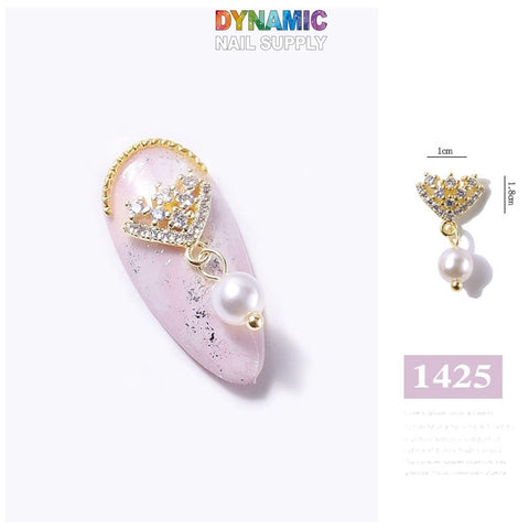 Introducing the Luxurious Jewelry for Nail Art Design - Part 4 from Dynamic Nail Supply, product number 1425. This exquisite decorative nail charm features a crown-shaped gold and silver embellishment adorned with small clear and yellow gems. A single pearl elegantly dangles from the crown, measuring 1.8 cm by 1 cm.