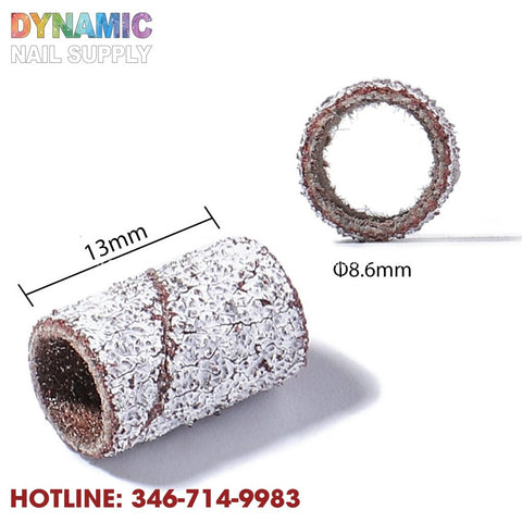 The image displays a pair of cylindrical sanding bands meant for manicure tools, featuring coarse textures. One is positioned upright while the other is laid horizontally. They measure 13mm in length and have a diameter of 8.6mm. The words "Dynamic Nail Supply" alongside the contact number, 346-714-9983, are printed at the bottom.