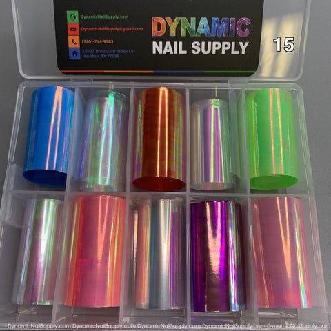 The Nail Art Design Foils - 15 by Dynamic Nail Supply come in a set of vibrant metallic colors, including blue, pink, green, and red. These foils are organized in a clear plastic box with the brand's logo and contact information on the lid, and the number 15 is prominently displayed in the top right corner.