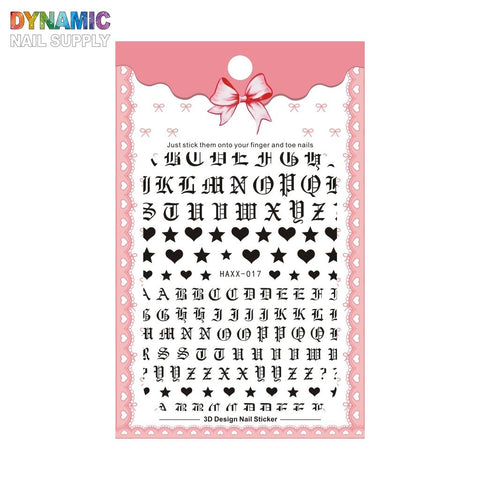 The image displays a set of Roman Alphabet Letters Stickers for Nails Art Design & Nails Decoration from Dynamic Nail Supply. These stickers feature black uppercase Gothic letters, along with small black hearts, stars, and cross shapes. The packaging is adorned with a pink lace border, has a ribbon at the top, and is labeled as 3D Design Nail Sticker.