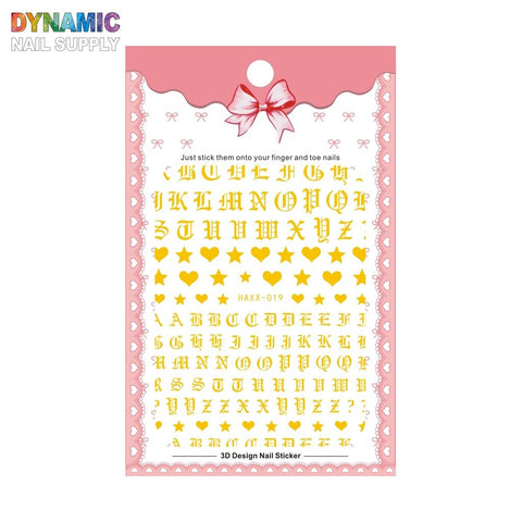A set of Roman Alphabet Letters Stickers for Nails Art Design & Nails Decoration, including gold Gothic letters and small symbols such as hearts and stars. The packaging is designed with a pink lace pattern, adorned with a bow at the top, and features the name Dynamic Nail Supply.