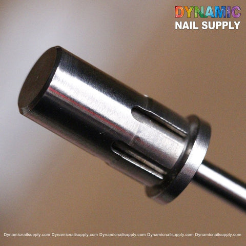 Close-up of a cylindrical, premium metal Easy-Off Sanding Band Mandrel featuring grooves that reflect light and display a shiny surface. In the background, the blurred Dynamic Nail Supply logo with rainbow colors appears in the top right corner.