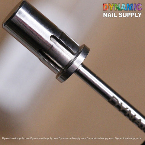 Close-up of the Easy-Off Sanding Band Mandrel, a high-quality nail drill bit featuring a cylindrical head with vertical grooves. The blurred background highlights "Dynamic Nail Supply" in colorful letters at the top right, while the website URL is neatly repeated along the bottom.