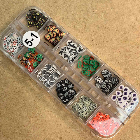 The Halloween Nails Glitter Sequins Organizer by Dynamic Nail Supply features 12 compartments filled with Halloween-themed polymer clay slices and a hint of glitter, showcasing pumpkins, ghosts, bats, and spiderwebs. It is arranged in four rows of three compartments and includes a white label marked 5-1 on the lid. Perfect for crafting unique Fall Nails 2021 designs!