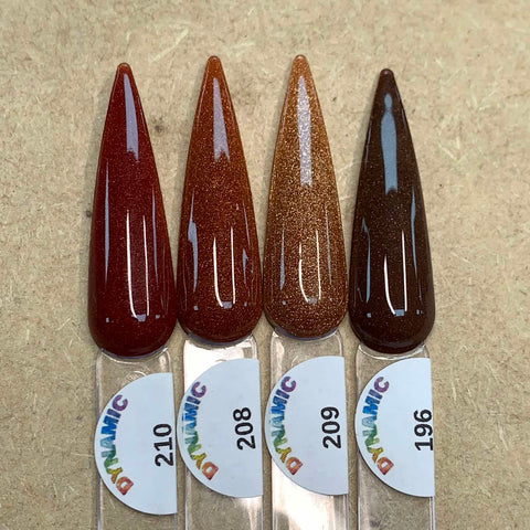 Displayed on a wooden surface are four elongated swatches from the 2024 New Fall Colors Acrylic Collection (Part 1) by Dynamic Nail Supply. The chip-resistant shades range from deep red, rusty orange, warm copper to dark brown. Each swatch features a circular label with the numbers 210, 208, 209, and 196 along with the word "DYNAMIC" in rainbow lettering.