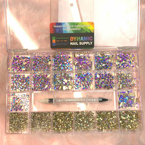 A transparent plastic organizer from Dynamic Nail Supply holds an assortment of colorful nail rhinestones. The top half dazzles with the AB K9 Crystal Rhinestone set, featuring 14 big shapes and 6 round shapes in iridescent designs, while the bottom displays gold-toned gems. A dual-ended rhinestone picker tool rests on top, accompanied by a Thank You card.
