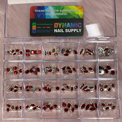 A clear plastic organizer with 24 compartments houses red nail charms and silver embellishments in diverse shapes from the 120 pcs Red Nail Charms set by Dynamic Nail Supply. The lid features a colorful card displaying business details along with a thank you message. It is all set against a wood-like background, ideal for highlighting your nail art design collection.