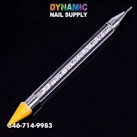 Against a black background, the Dual-ended Nail Art Wax Dotting Pen Picking Up Rhinestone is displayed. This tool, featuring a transparent handle filled with shimmering rhinestones, has a yellow cone-shaped tip on one end and a pointed metal tip on the other. The text "Dynamic Nail Supply" and the phone number 346-714-9983 are prominently visible.