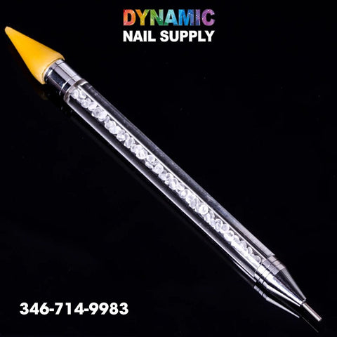 A Dual-ended Nail Art Wax Dotting Pen Picking Up Rhinestone is displayed on a black background, featuring transparent handles filled with tiny white crystals. One end boasts a yellow silicone tip designed for precise rhinestone placement, and the other end has a metallic pointed tip. The brand name "Dynamic Nail Supply" is prominently featured at the top, along with the contact number 346-714-9983 at the bottom left.