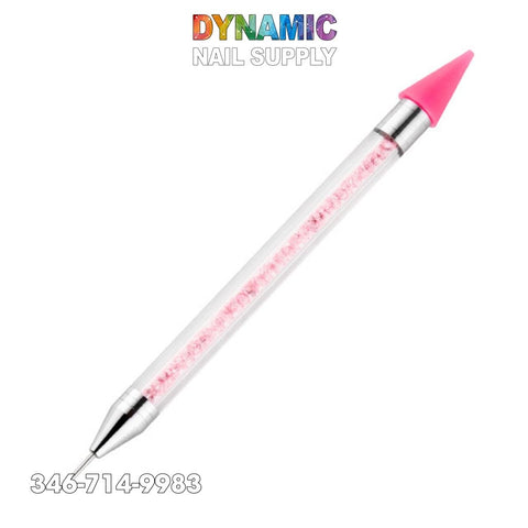 This image showcases the Dual-ended Nail Art Wax Dotting Pen Picking Up Rhinestone by Dynamic Nail Supply, ideal for crafting intricate designs. It features a clear body filled with pink beads, one end equipped with a fine metal point perfect for rhinestones, and the other end has a wax dotting pen with a pink silicone tip. The top is decorated with "DYNAMIC NAIL SUPPLY" in colorful letters.