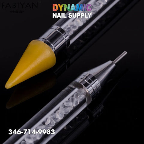 Close-up image of two nail art tools on a black background. The upper tool, part of the Dual-ended Nail Art Wax Dotting Pen Picking Up Rhinestone set, features a yellow tip, while the lower one has a fine metal tip. Both handles are transparent and filled with small white crystals akin to rhinestones. Dynamic Nail Supply is displayed at the top with 346-714-9983 below.