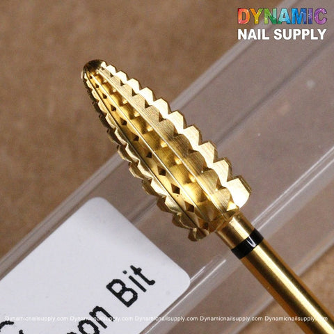 Close-up of a gold, cone-shaped drill bit featuring a ridged, stepped design. This XC Typhoon Bit - Dynamic Drill Bit is marked with Corn Bit and rests on a clear plastic case showcasing the brand name Dynamic Nail Supply in colorful text at the top right corner.